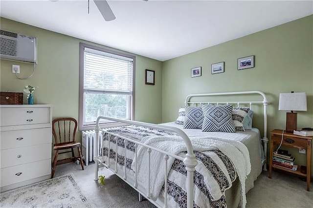 bedroom with a wall unit AC, ceiling fan, radiator, and light colored carpet