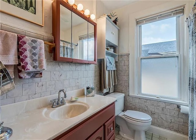 bathroom with tile walls, vanity, toilet, and tile patterned floors