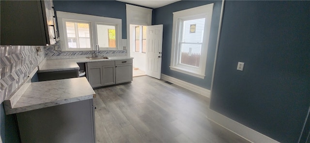 kitchen with decorative backsplash, gray cabinets, light wood-type flooring, and sink