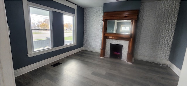 unfurnished living room featuring a fireplace, plenty of natural light, and dark wood-type flooring