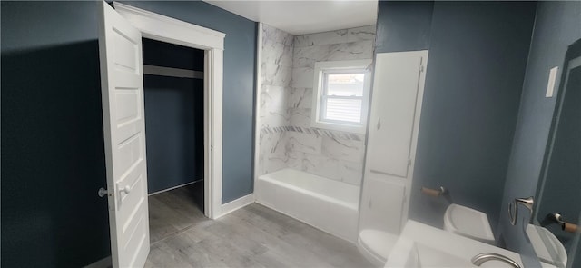 bathroom featuring hardwood / wood-style flooring, tiled shower / bath, and toilet