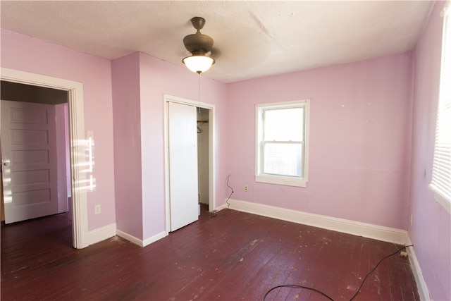 unfurnished bedroom featuring ceiling fan, a textured ceiling, a closet, and dark hardwood / wood-style flooring