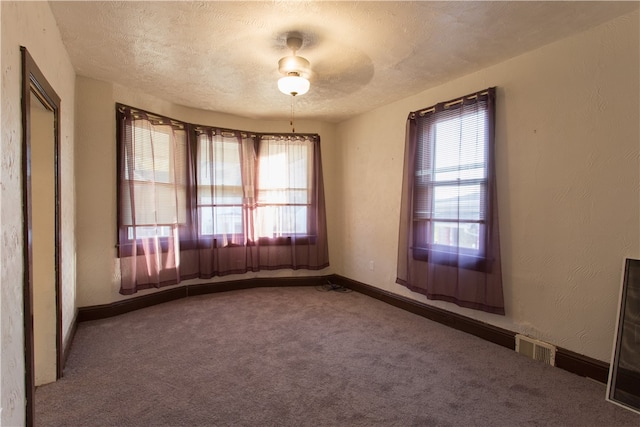 empty room featuring ceiling fan, a textured ceiling, and carpet flooring