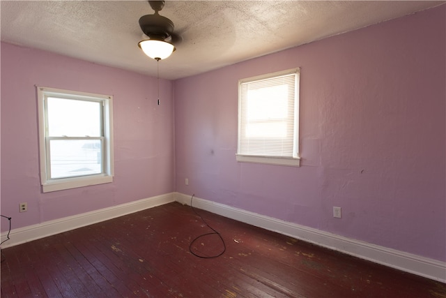 unfurnished room with dark wood-type flooring, ceiling fan, a healthy amount of sunlight, and a textured ceiling