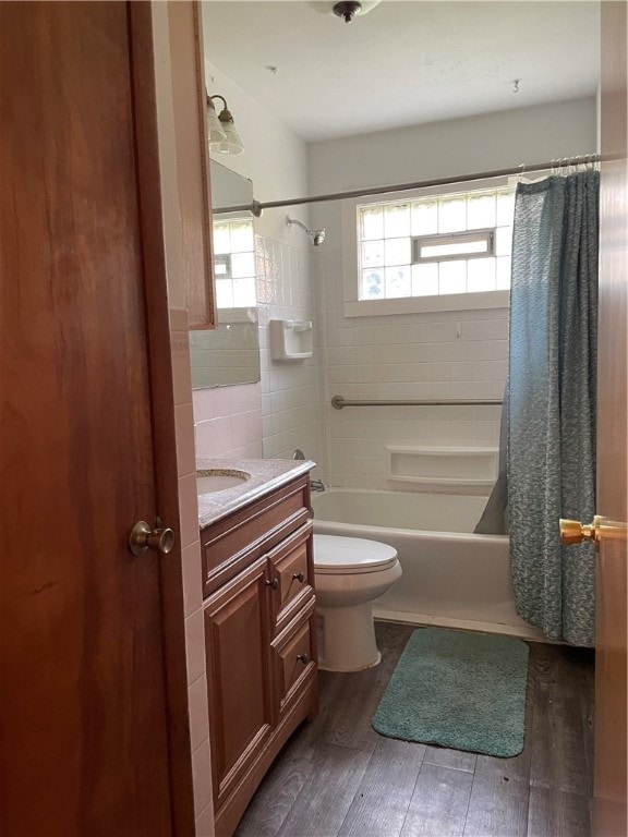 full bathroom with tile walls, wood-type flooring, vanity, shower / bath combo, and toilet