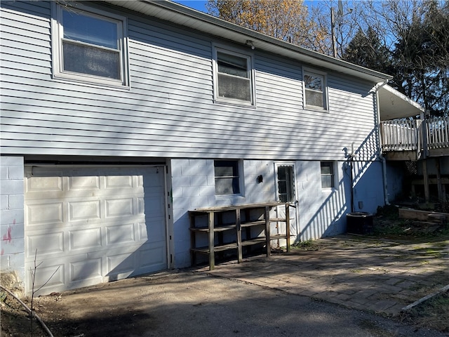 back of property featuring a garage and a wooden deck