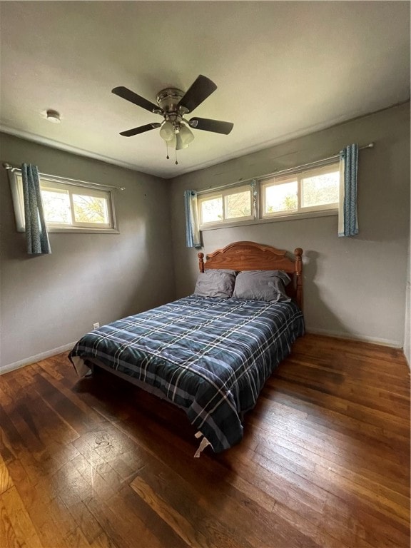 bedroom with multiple windows, dark hardwood / wood-style flooring, and ceiling fan