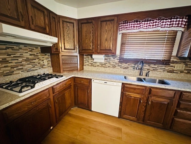 kitchen featuring white appliances, sink, and backsplash