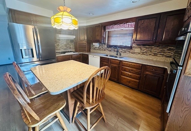 kitchen featuring white dishwasher, sink, stainless steel fridge with ice dispenser, pendant lighting, and light wood-type flooring