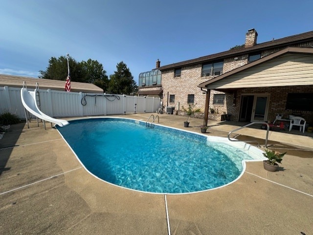 view of swimming pool with a patio, cooling unit, and a water slide