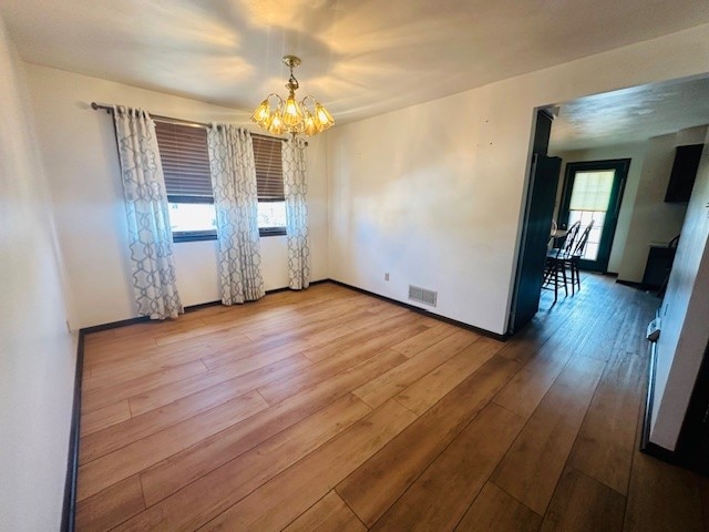 spare room featuring hardwood / wood-style floors and an inviting chandelier