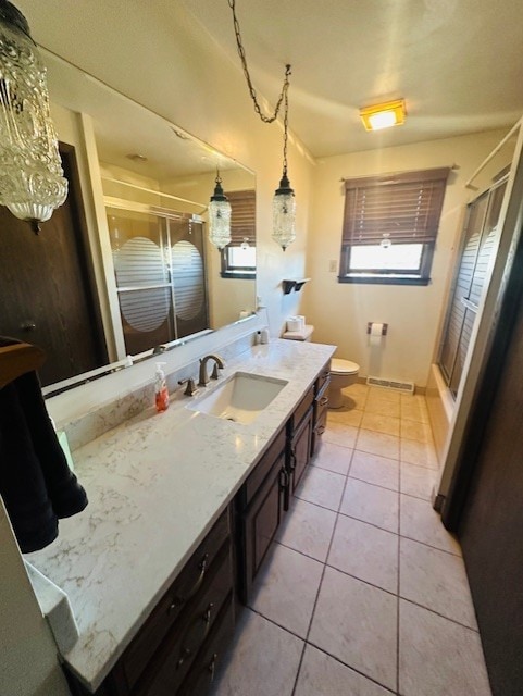 bathroom with vanity, a shower with shower door, tile patterned floors, and toilet