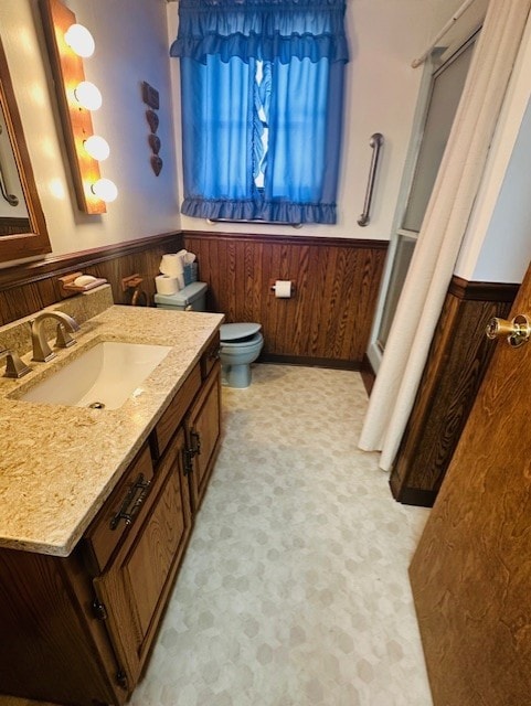 bathroom with vanity, wooden walls, and toilet