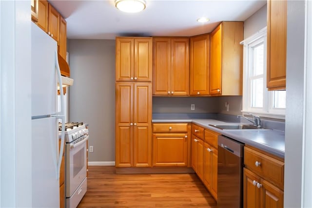 kitchen with white appliances, sink, and light hardwood / wood-style flooring