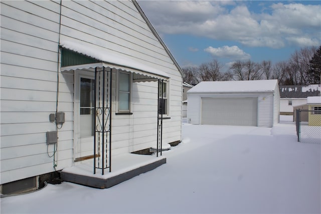 view of snowy exterior featuring an outdoor structure and a garage