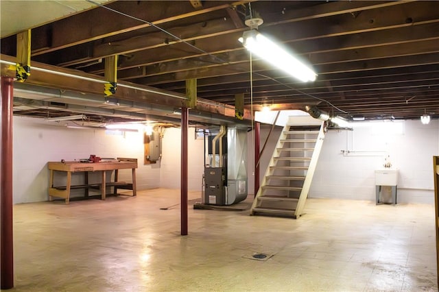 basement with electric panel, heating unit, and sink