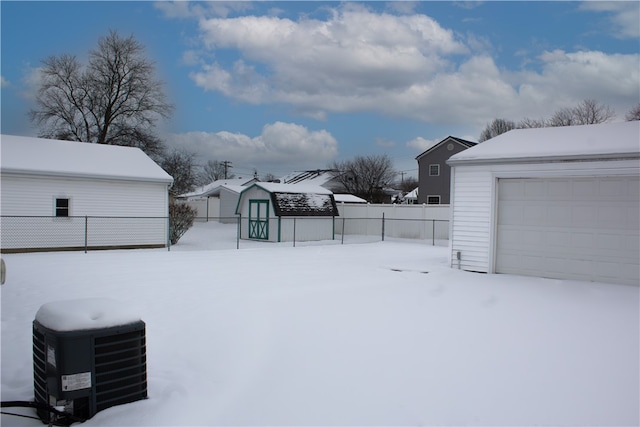 yard layered in snow with an outdoor structure and central AC unit