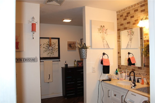 bathroom with washer / dryer, vanity, decorative backsplash, and hardwood / wood-style flooring