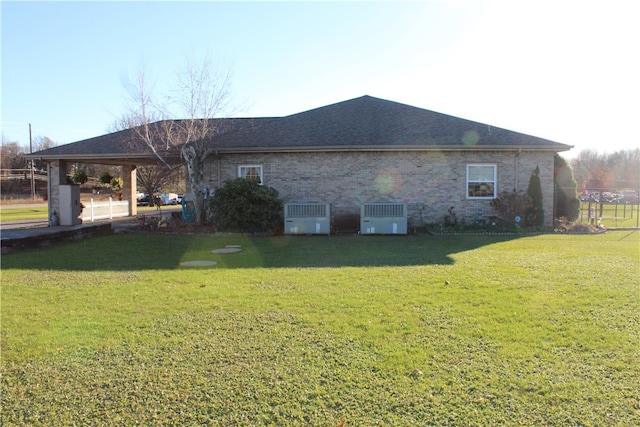 back of property with central AC unit and a yard