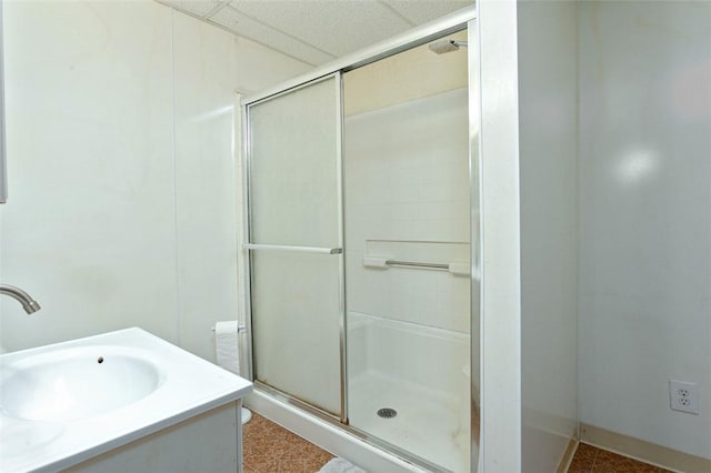 bathroom with a drop ceiling, an enclosed shower, and vanity