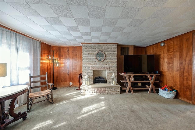 carpeted living room featuring a brick fireplace and wooden walls