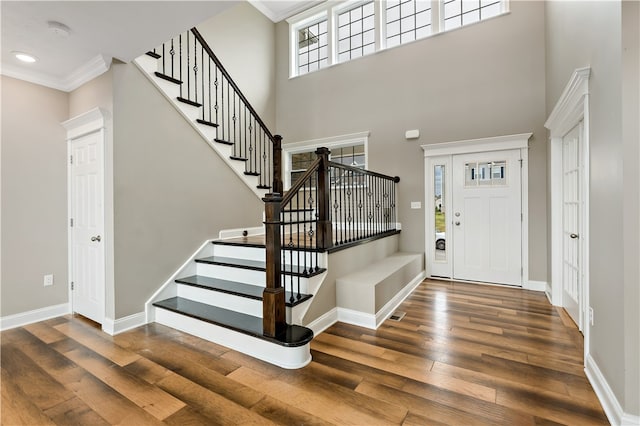 foyer with ornamental molding, dark wood-type flooring, and a high ceiling