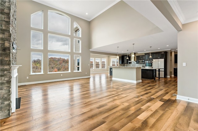 unfurnished living room featuring a fireplace, a wealth of natural light, a high ceiling, and light hardwood / wood-style flooring