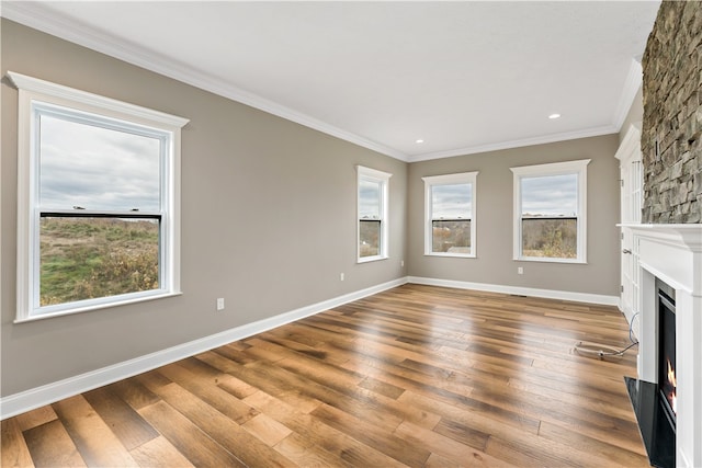 unfurnished living room featuring crown molding, a fireplace, a healthy amount of sunlight, and light wood-type flooring