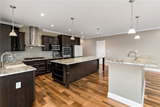 kitchen with stainless steel appliances, wall chimney exhaust hood, sink, and a center island