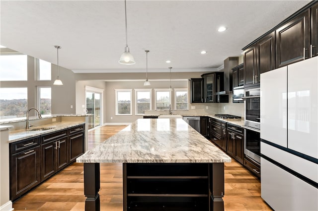 kitchen with sink, appliances with stainless steel finishes, light hardwood / wood-style flooring, a kitchen island, and pendant lighting