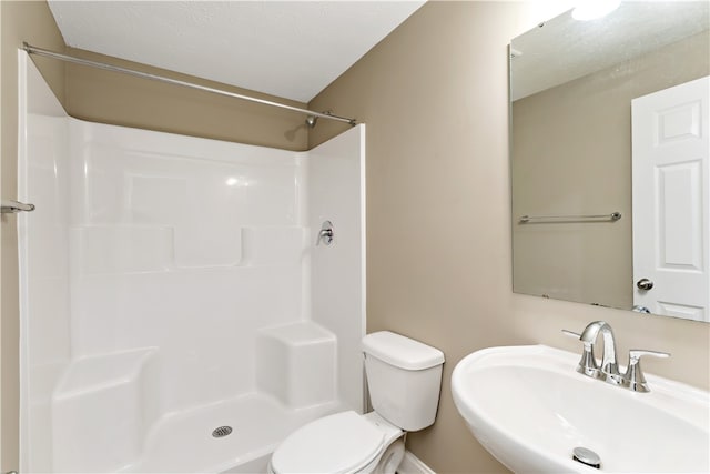 bathroom featuring toilet, sink, walk in shower, and a textured ceiling