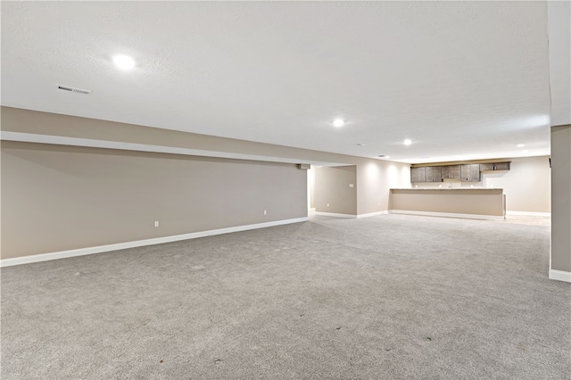 basement with a textured ceiling and light carpet