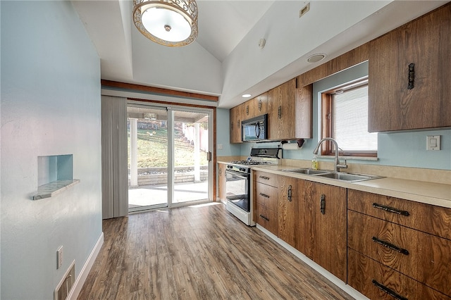 kitchen with hardwood / wood-style floors, plenty of natural light, lofted ceiling, and white gas range oven