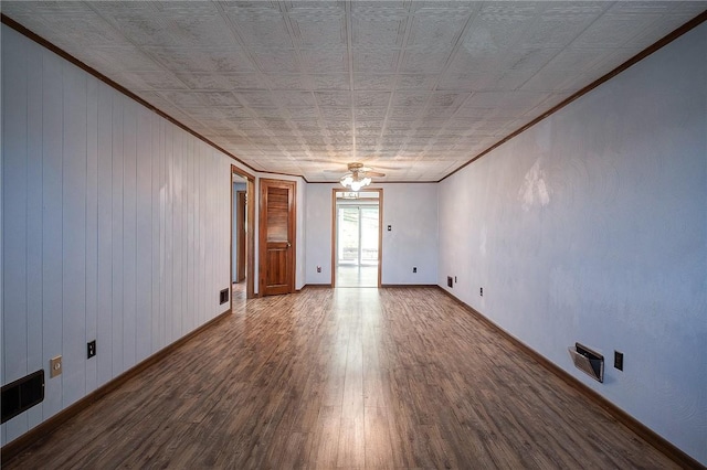 unfurnished room with hardwood / wood-style flooring, ceiling fan, ornamental molding, and wooden walls