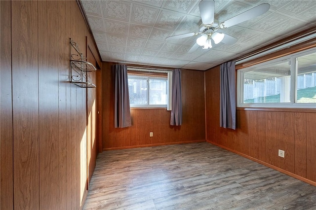 spare room with wood walls, ceiling fan, and light hardwood / wood-style floors