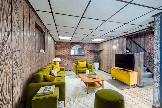 living room featuring wooden walls and a drop ceiling