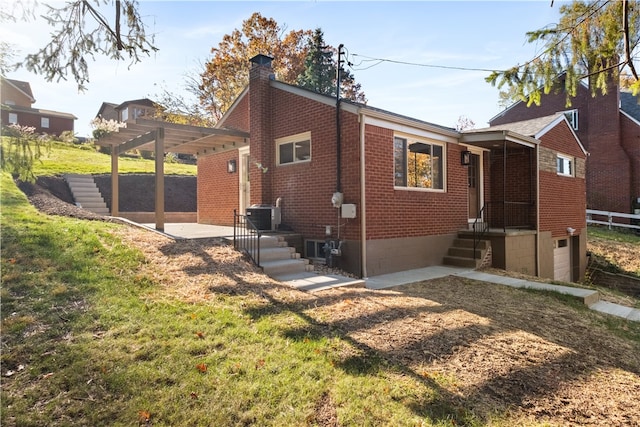 back of property with a lawn, a pergola, and central AC