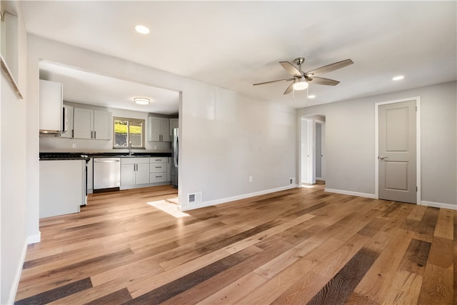 unfurnished living room with ceiling fan, sink, and light hardwood / wood-style floors