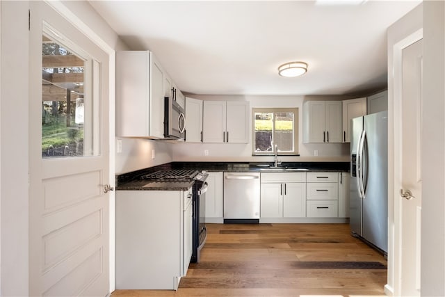 kitchen with white cabinets, sink, light wood-type flooring, and appliances with stainless steel finishes