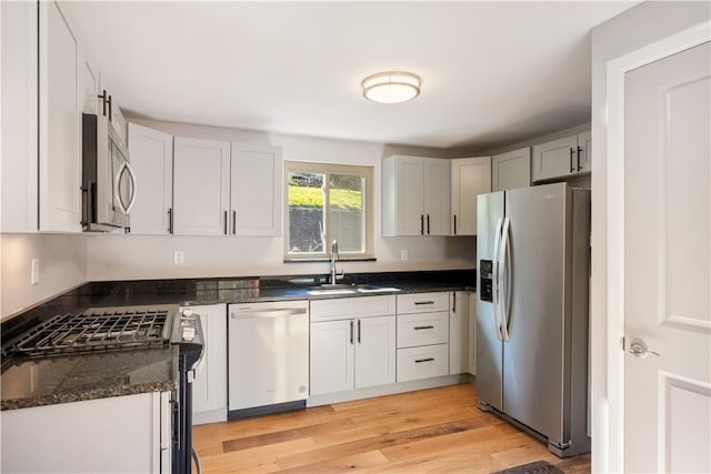 kitchen featuring light hardwood / wood-style floors, stainless steel appliances, sink, and dark stone countertops