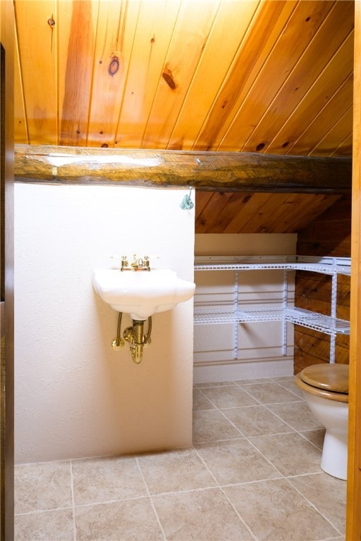 bathroom featuring toilet, sink, tile patterned floors, and wooden ceiling