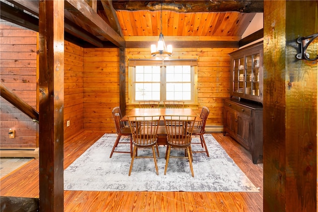 dining space with wood walls, a baseboard radiator, light hardwood / wood-style flooring, and vaulted ceiling with beams