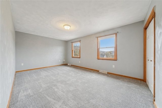 unfurnished bedroom with light colored carpet and a closet