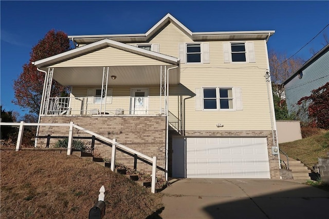 view of front of house with brick siding, covered porch, stairway, a garage, and driveway