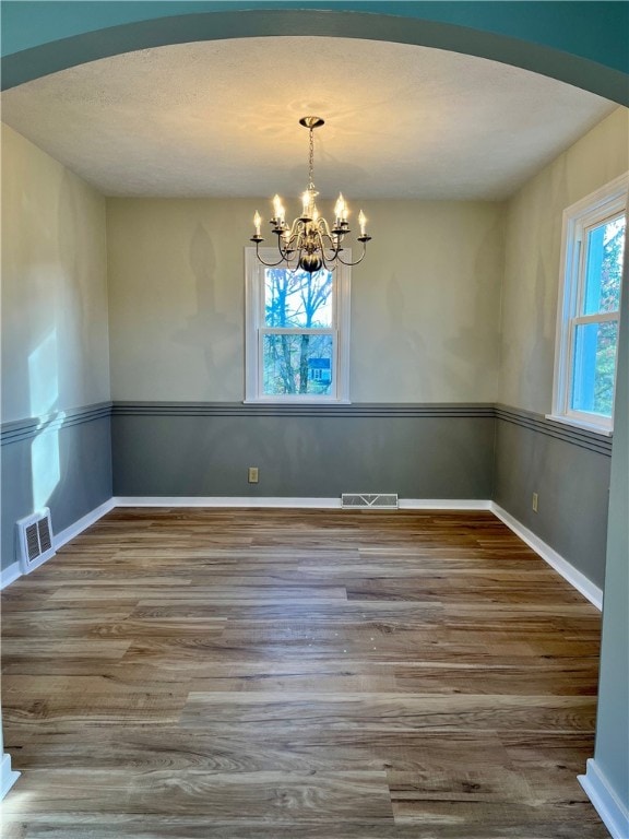 unfurnished dining area with an inviting chandelier and hardwood / wood-style flooring