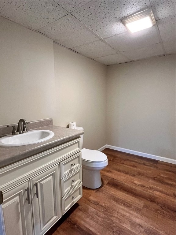 bathroom featuring hardwood / wood-style floors, a paneled ceiling, vanity, and toilet