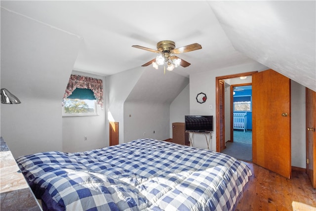 bedroom featuring ceiling fan, multiple windows, vaulted ceiling, and wood-type flooring