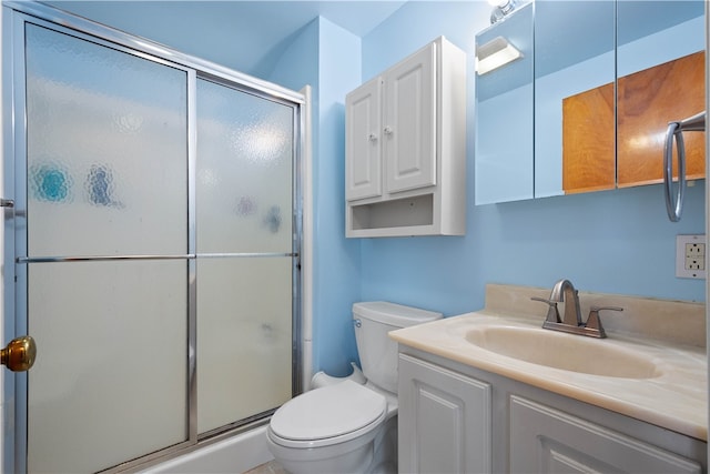 bathroom with vanity, toilet, and a shower with door