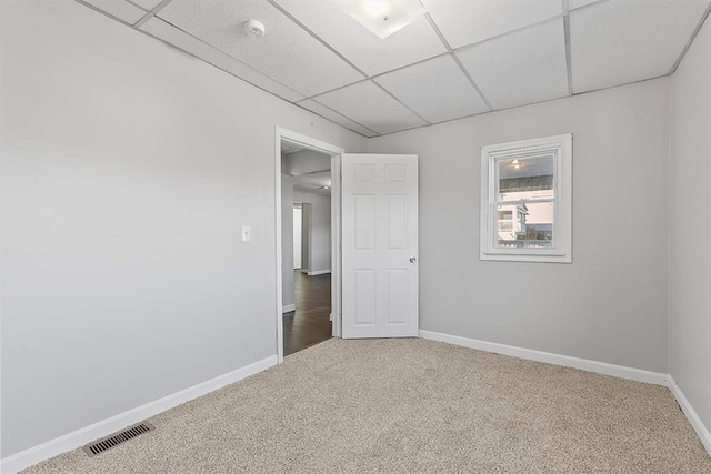 carpeted spare room featuring a paneled ceiling