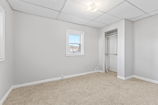 unfurnished bedroom featuring light carpet, a closet, and a drop ceiling